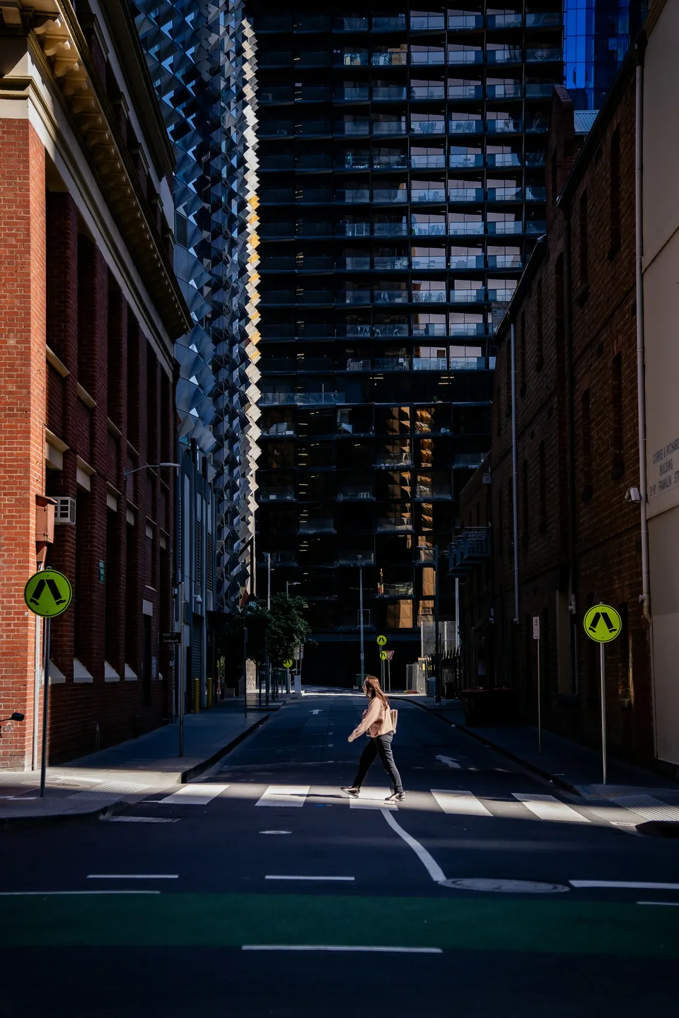A person crossing a sunlit street in Melbourne